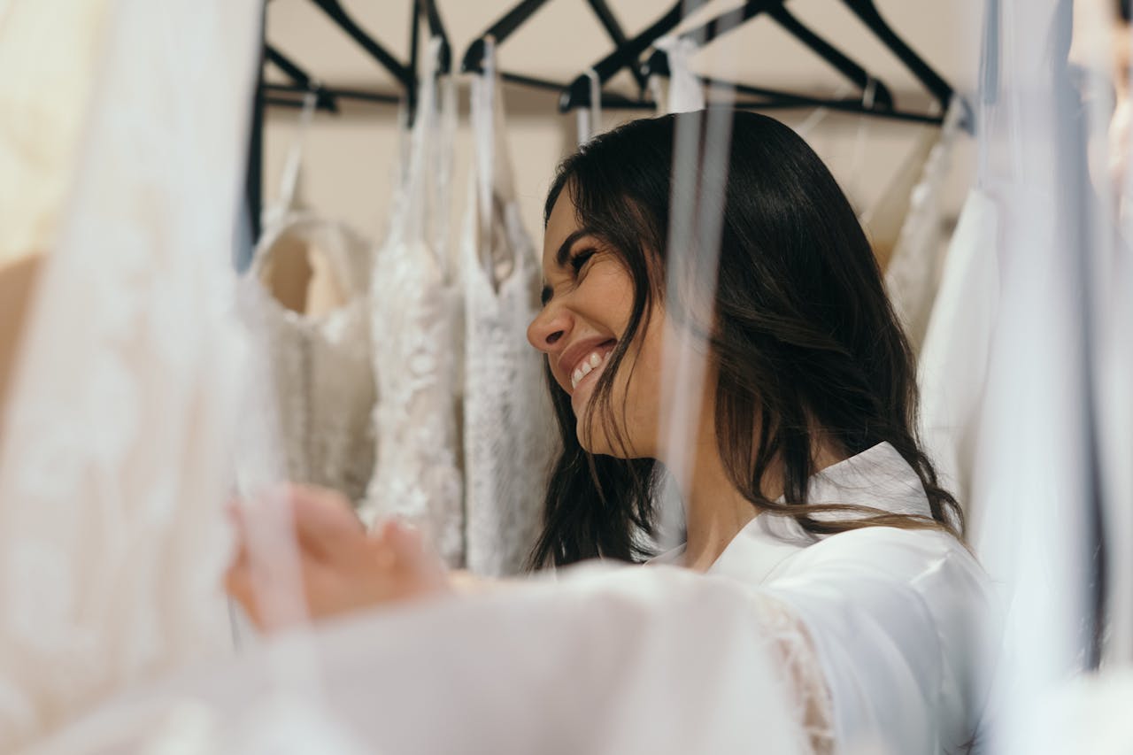 Smiling woman trying on wedding dresses in a bridal boutique.